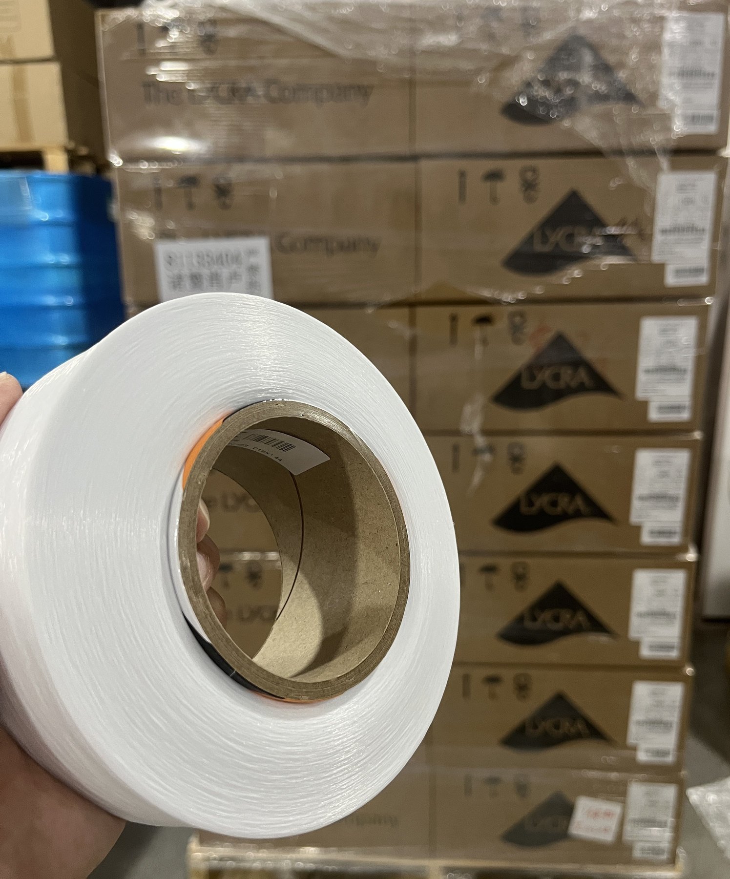 Raw material yarn spool with packaged materials in the background